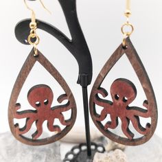 Octopus Earrings in a red wine wash. Laser cut from 3mm Birch and finished with a satin varnish. Back of earrings are single color french roast. Available with silver or gold hardware. Earrings are very light. Earrings are handmade, each pair is unique and may contain variations in wood grain. Thank you for viewing my item, please feel free to ask any questions or reach out for quantity pricing.Materials: Wood,Stainless steel Octopus Earrings, Wood Dangle Earrings, French Roast, Light Earrings, Ocean Lover, Sea Ocean, Sea And Ocean, Laser Cut Wood, Scroll Saw