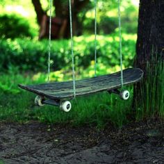 a skateboard that is sitting in the grass near a tree with wheels attached to it