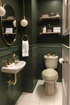 a bathroom with green walls and white tile flooring, along with gold fixtures on the wall