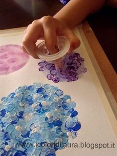 a child's hand is holding a bottle over some buttons on a piece of paper