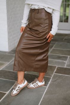 Expertly crafted with a high waistline, this brown faux leather midi skirt is both stylish and functional. Complete with pockets for added convenience, this skirt is the perfect addition to any wardrobe. Add a touch of sophistication to your outfit with this must-have piece! 100% polyurethane Model is 5'4" with a 25" waist and 38" hips and wearing a small. Size recs: 2-4 S 4-6 M 8-10 L Faux Leather Midi Skirt, Maxi Tops, Leather Midi Skirt, Dresses By Length, Short Rompers, Skirt Pants, Set Dress, Sneaker Boots, Dresses For Sale