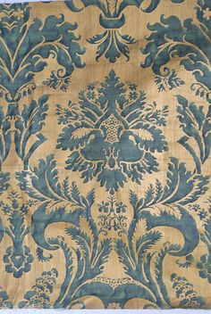 an old blue and gold wallpaper with floral designs on it's edges,