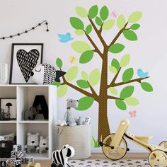 a child's room with a tree wall decal and toys on the floor