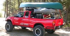 a red pick up truck with a green kayak on top of it's roof