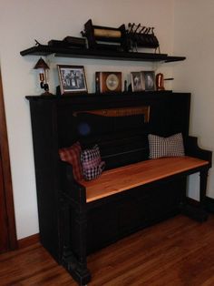 a black piano sitting on top of a hard wood floor next to a shelf filled with pictures