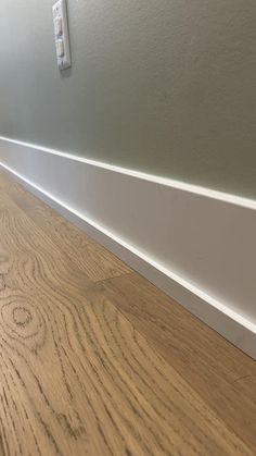 a wood floor with white trim on the wall and wooden flooring in front of it