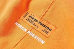 an orange polo shirt with the name heron preston printed on it's chest pocket