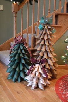 three paper christmas trees sitting on top of a wooden table next to a stair case