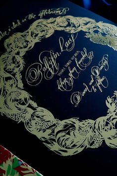 an ornate wedding card with gold foil on it's blue cover and black background