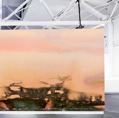 an abstract painting on display in a white room with wood flooring and metal beams