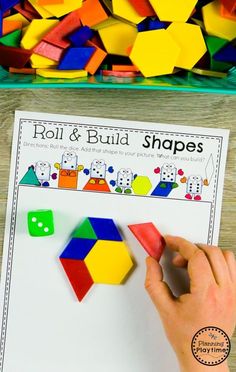 a hand holding a piece of colored paper next to a pile of shapes and numbers