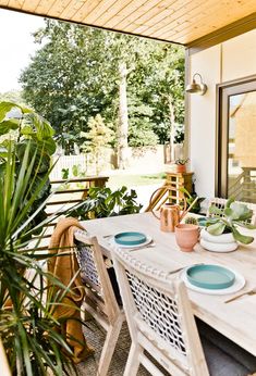 a wooden table sitting on top of a patio next to a green potted plant