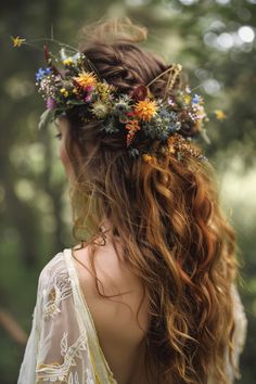 a woman with long hair wearing a flower crown in the woods, looking back at the camera