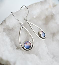 These celestial inspired earrings were created with 8mm galaxy images sealed behind glass domes and set in antique silver tear drop shape charms. Finished with stainless steel earring hooks. Charm size: 32x18mm These are a great gift for any space lover! All of my jewelry comes packaged ready to gift in a cotton filled kraft jewelry box with elastic ribbon. Note: These glass dome earrings are water resistant; however not water proof. It is recommended that they are removed before swimming or sho Stainless Steel Teardrop Earrings For Gift, Teardrop Stainless Steel Earrings For Gifts, Hypoallergenic Metal Teardrop Pendant Jewelry, Hypoallergenic Teardrop Pendant Jewelry, Spiritual Teardrop Sterling Silver Earrings, Spiritual Sterling Silver Teardrop Earrings, Space-themed Dangle Jewelry Gift, Adjustable Metal Teardrop Earrings Gift, Adjustable Metal Teardrop Earrings For Gift