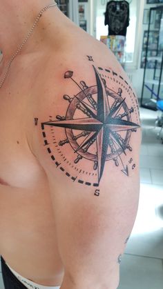 a man with a compass tattoo on his shoulder