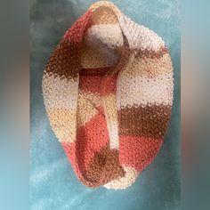 a crocheted hat is laying on top of a blue cloth with a brown, white and red stripe