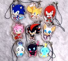 six key chains with cartoon characters on them sitting on a white surface in the shape of an animal