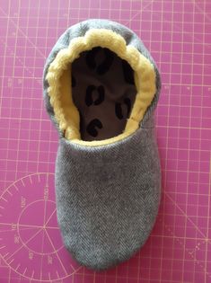 a pair of baby shoes sitting on top of a pink cutting board next to a ruler