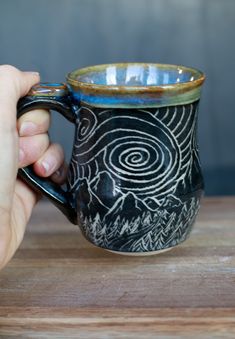 a hand holding a black and blue coffee mug