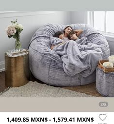 two women laying in a bean bag chair with a blanket on it and some candles