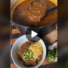 a bowl of chili and cheese next to a skillet filled with meatballs, green peppers and shredded cheese