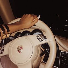 a woman driving a car with her hand on the steering wheel and another person's wrist