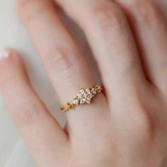 a woman's hand wearing a gold ring with three small flowers on it,