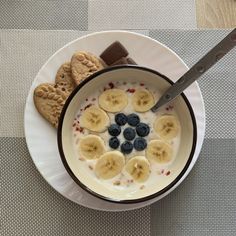 a bowl of oatmeal with bananas, blueberries and cookies on the side