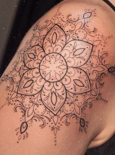 the back of a woman's shoulder with an intricate tattoo design on her arm