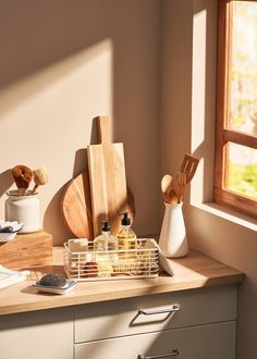 kitchen utensils and wooden cutting boards sit on a counter in front of a window