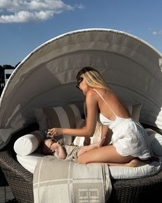 a woman sitting on top of a bed next to a baby in a white dress