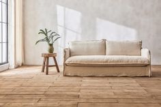 a white couch sitting next to a wooden table on top of a hard wood floor