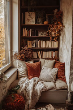 a window seat with pillows and blankets on it in front of a bookshelf