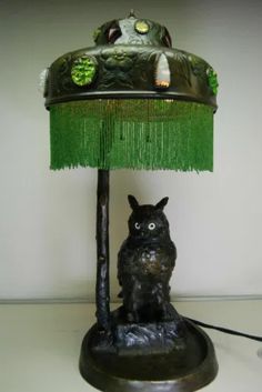 an owl lamp sitting on top of a table next to a green fringed shade