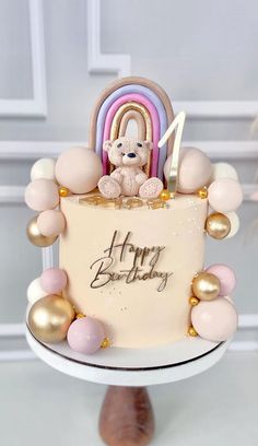 a birthday cake decorated with balloons and a teddy bear