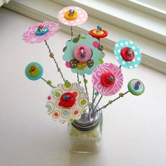 a vase filled with buttons and pins on top of a window sill next to a window