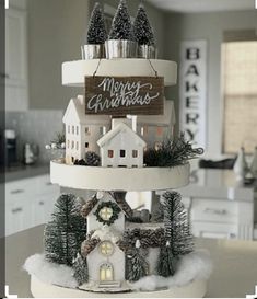 a three tiered christmas cake decorated with houses and trees