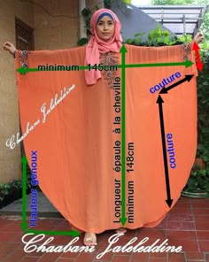 a woman in hijab holding up an orange shawl with words on it