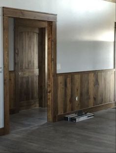 an empty room with wood paneling on the walls and wooden doors in the middle