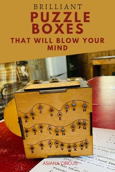 a wooden puzzle box sitting on top of a table next to a piece of paper