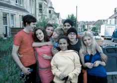 a group of young people standing next to each other in front of some buildings and trees