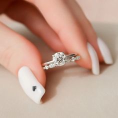 a woman's hand with white nails and a diamond ring on her finger,