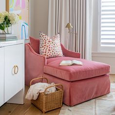 a living room with a pink chair and ottoman