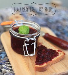 a jar of jam sitting on top of a wooden cutting board next to a slice of bread