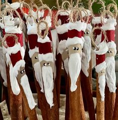 several wooden santa clauss are hanging from twine with jumbo sticks attached to them