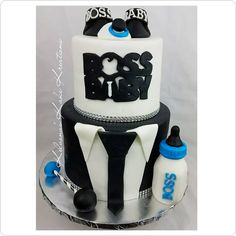 a three tiered cake decorated with black and white fondant, blue accents and the words boss on top