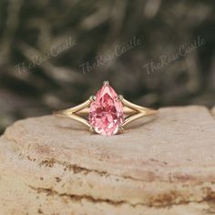 a pink diamond ring sitting on top of a rock