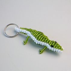 a green and white beaded alligator keychain sitting on top of a table