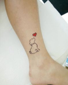 a small dog with a heart tattoo on its leg is sitting on a bed and it's paw is in the shape of a balloon