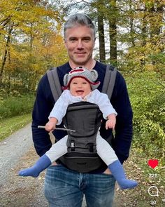 a man holding a baby in a carrier